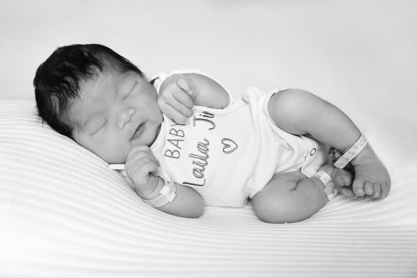 Newborn Laila sleeping in a Baby Laila onesie