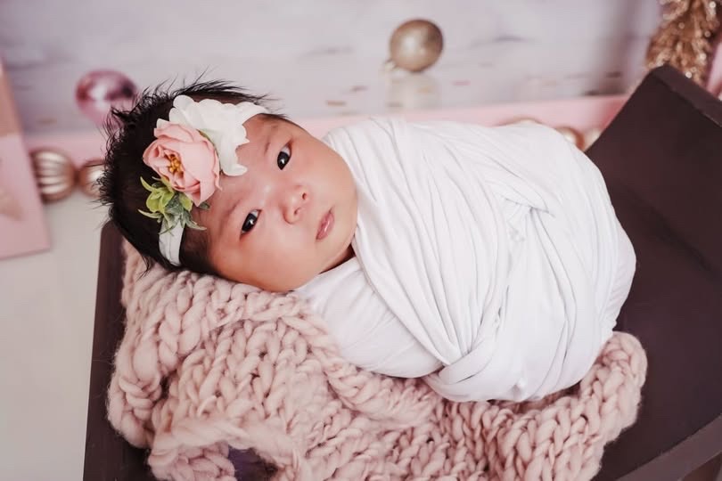 Laila swaddled with a flower headband